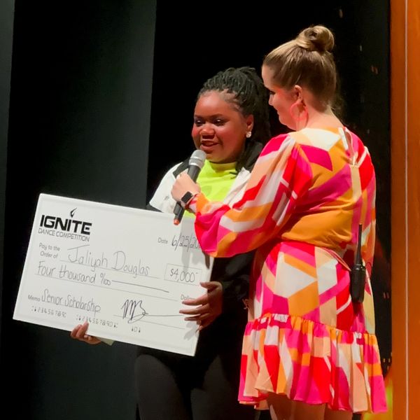 Senior dancer accepting a check from Meghan for $4,000 onstage at Ignite Dance Competition