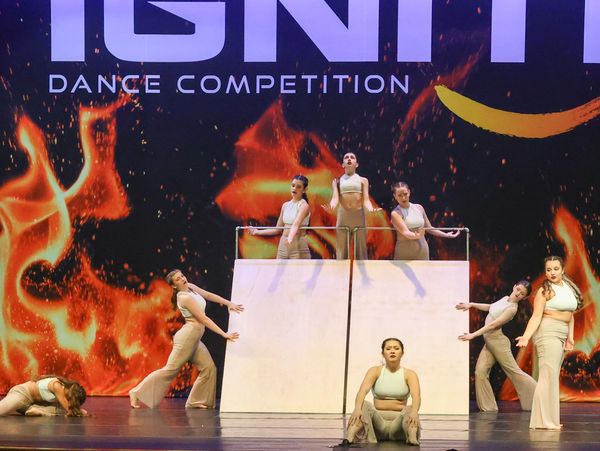 Dancers performing at IGNIT dance competition with fire backdrop.