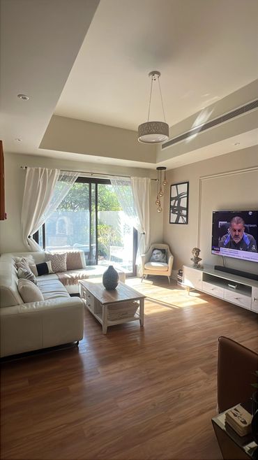 Bright modern living room with white furniture and wooden flooring.