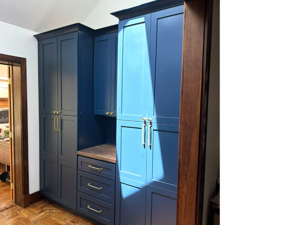 Blue built-in cabinets with brass handles in a room with wood flooring and trim.
