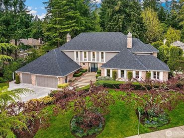 Spacious suburban house with manicured garden and tall trees.