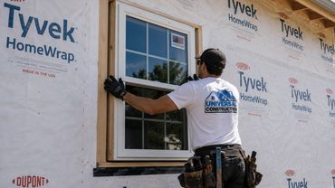Worker installing a window on a house under construction.