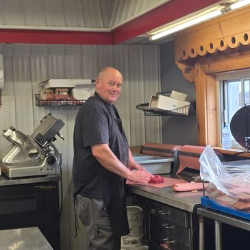 Man slicing meat in a butcher shop.