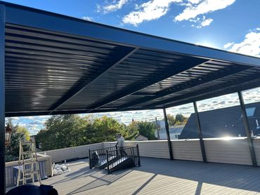 Modern rooftop deck with a metal pergola and clear blue sky.
