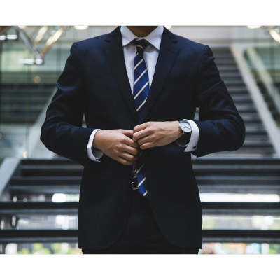 A man adjusts his suit jacket in front of stairs.
