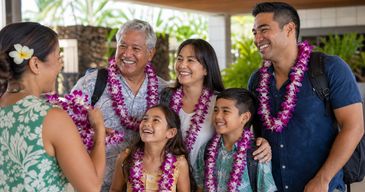 Family and friends receiving fresh orchid leis during a Big Island airport arrival