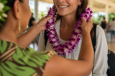 Hawaii lei greeter placing a fresh orchid lei around an arriving traveler