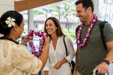 Couple receiving fresh orchid leis from a Hawaii airport greeter for an Oahu arrival