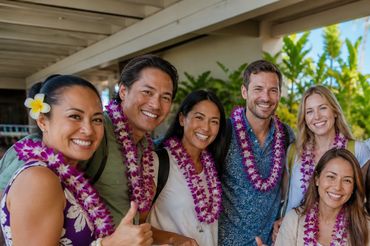 Large group of travelers wearing fresh orchid leis after a Hawaii airport welcome