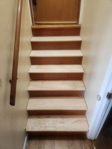 Wooden stairs with newly installed light wood treads and old darker risers.