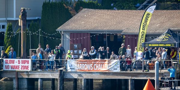 Crowd gathers on a dock for the Narrows Challenge canoe event.