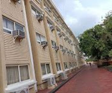 Long building wall with multiple air conditioners and a red brick pathway.