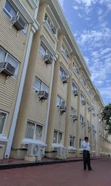 Tall building with multiple air conditioners and a person standing outside.