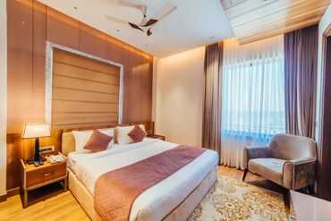 Elegant hotel room with a large bed, soft lighting, and a cozy armchair.