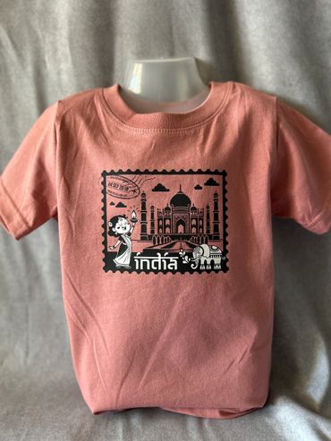 A pink t-shirt with a black print of the Taj Mahal, an elephant, and a woman in traditional attire.