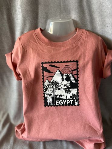 Pink t-shirt with Egypt-themed print including pyramids and the Sphinx.