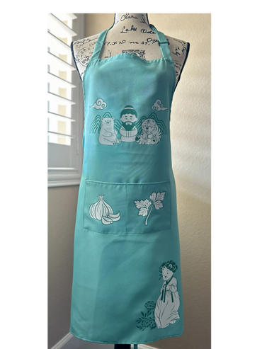 A teal apron with cute cartoon illustrations of a bear, tiger, garlic, parsley, and a person in traditional attire.