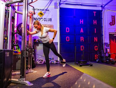 Woman stretching her leg using gym equipment in a fitness center.