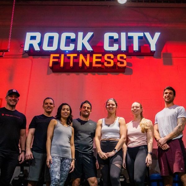Rock City Fitness group training clients posing in front of studio sign.