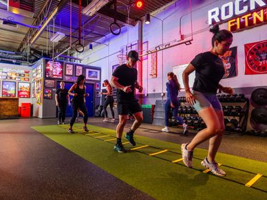 Group training session with agility ladder drills in a vibrant gym.