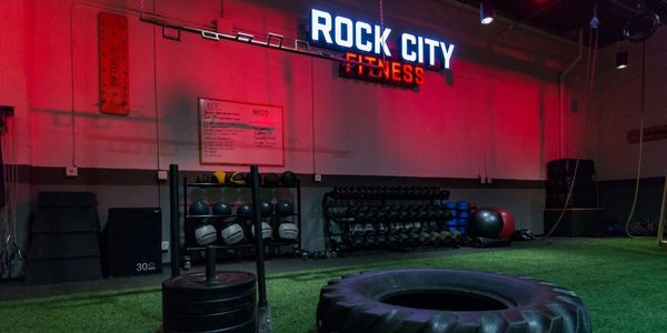 Rock City Fitness workout floor with sled, tire, medicine balls and dumbbells.