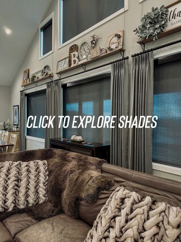 Cozy living room with plush pillows, soft throws, and decorative shelves above large windows.