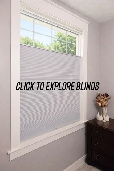 Half-closed white window blinds with a view of green trees outside.