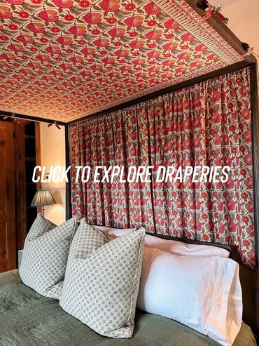 Cozy bed with floral canopy and patterned pillows in warm bedroom.