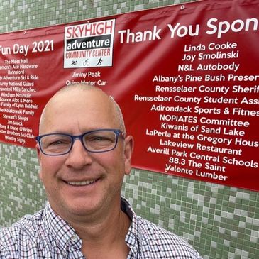 John Slyer in front of a fundraising banner at the SHAC Center