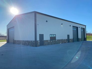 Modern industrial building with metal siding and stone accents under bright sunlight.