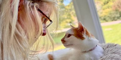 A woman and a cat looking at each other closely.