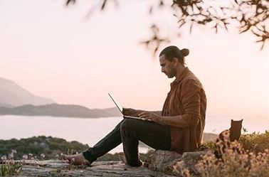 Gentleman outside in nature on laptop.