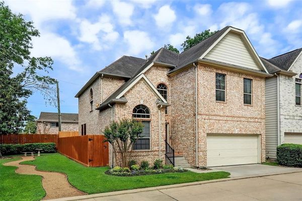 Brick two-story house with a well-kept lawn.