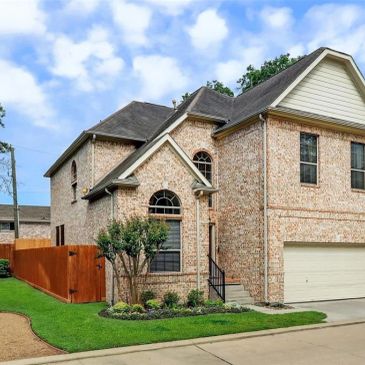 Brick two-story house with a well-kept lawn.