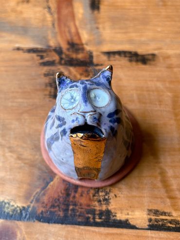 Incense burner shaped like the bust of a cat w/ an open mouth & gold flowing from mouth to base