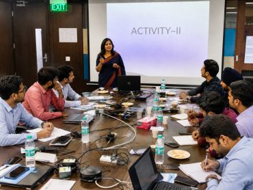 A woman leads a group activity in a conference room with attentive participants.