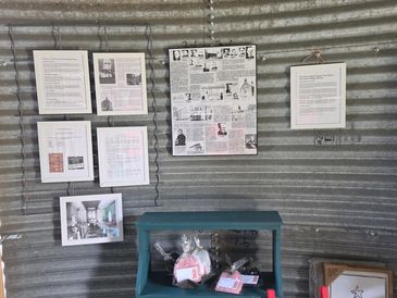 A display of framed documents and gift items on a corrugated metal wall.