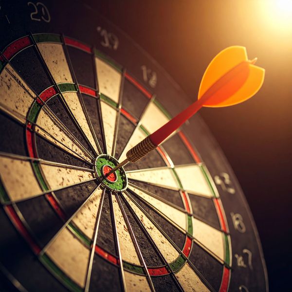 A dart hitting the bullseye on a dartboard with warm lighting, mission, goals, target, strategy