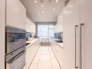 Sleek modern kitchen with white cabinetry and appliances.