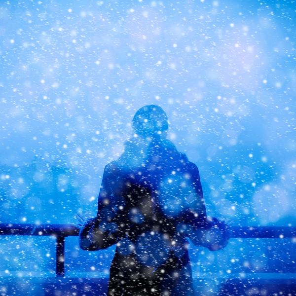 A woman stands alone in the snow, looking out into icy nothingness.