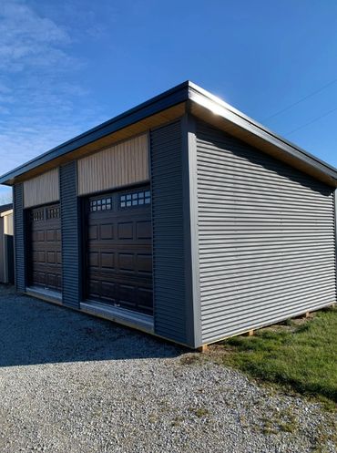Modern gray garage with two large doors under a clear blue sky.