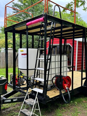A black metal-framed platform with tanks, a ladder, and a red hose reel outdoors.