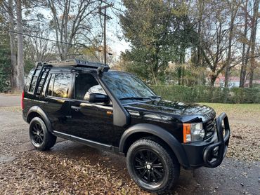 Black Land Rover Discovery with off-road modifications parked outdoors.