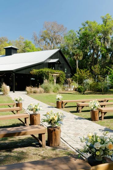 outdoor wedding ceremony florals on stumps lining the sides of aisle.