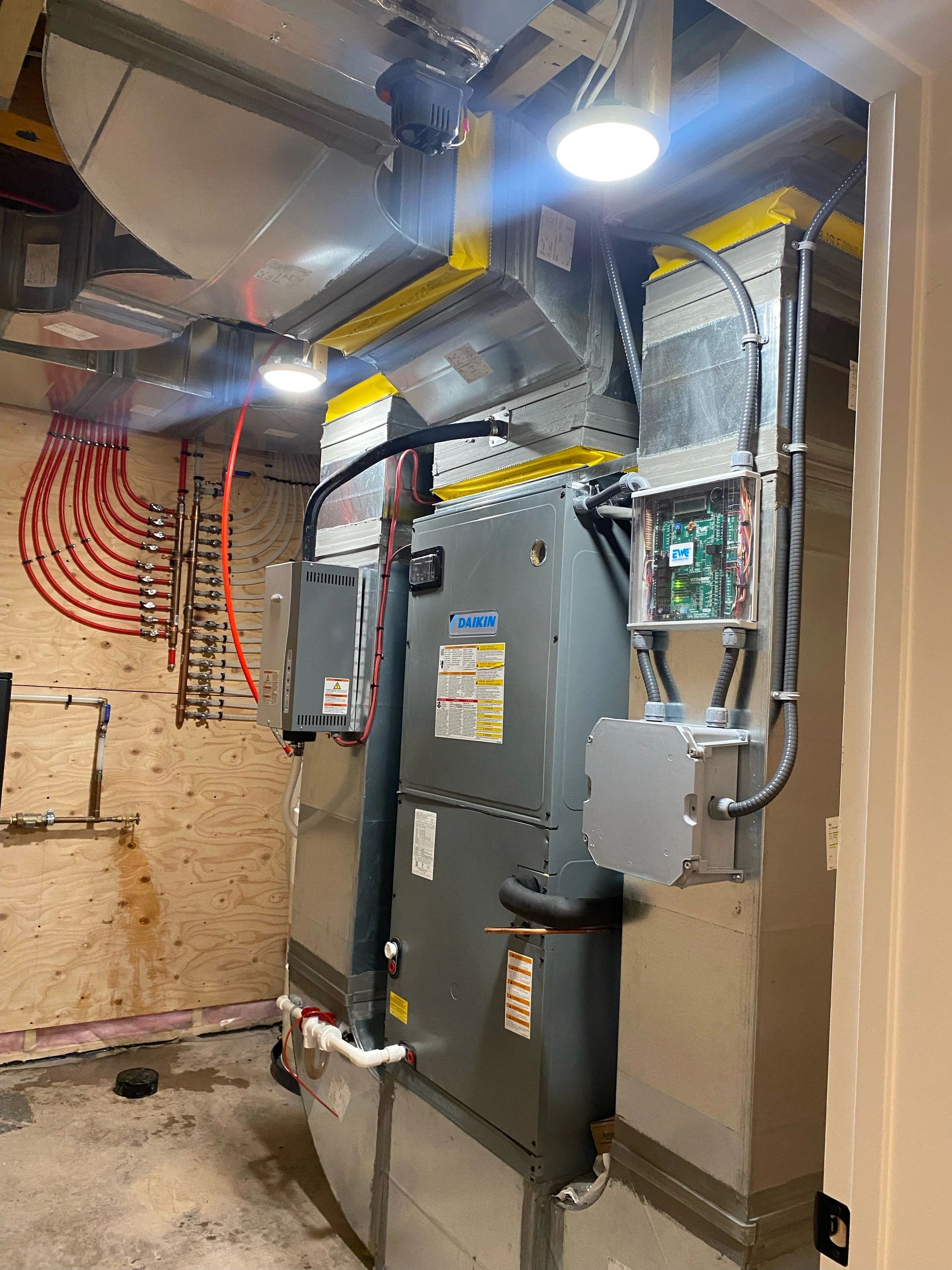A modern HVAC system setup in a utility room with Daikin equipment and organized piping.