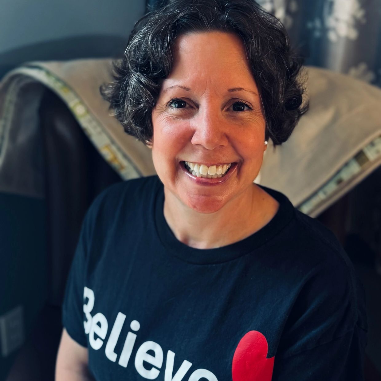 Smiling woman wearing a "Believe" shirt.