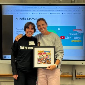 Two smiling women holding a Teacher of the Year award.