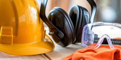 Construction safety gear including helmet, earmuffs, goggles, and gloves.