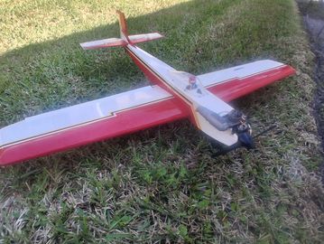 A red and white model airplane on grass.