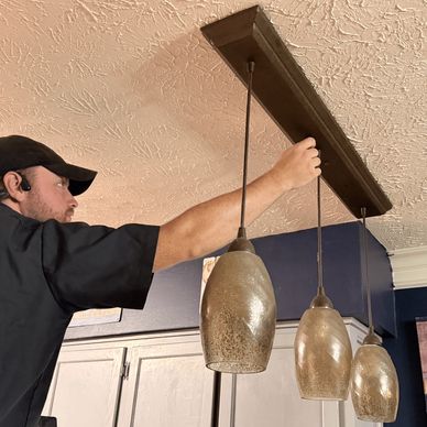 A man installs pendant lights on a ceiling.